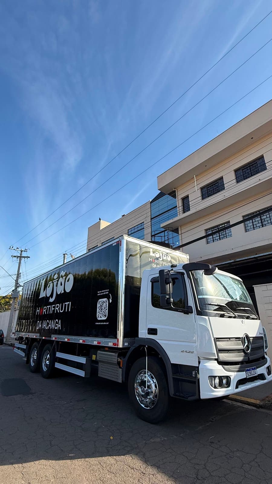 Caminhão preto do Lojão da Iacanga, com a marca nova, chegando com produtos frescos