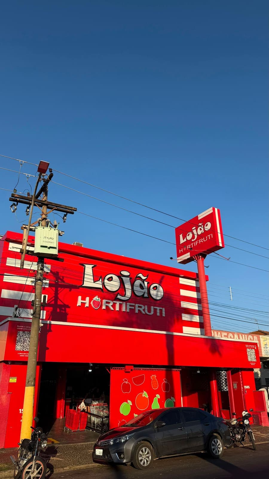 Fachada do Lojão vista da esquina, com o letreiro vermelho e o céu azul